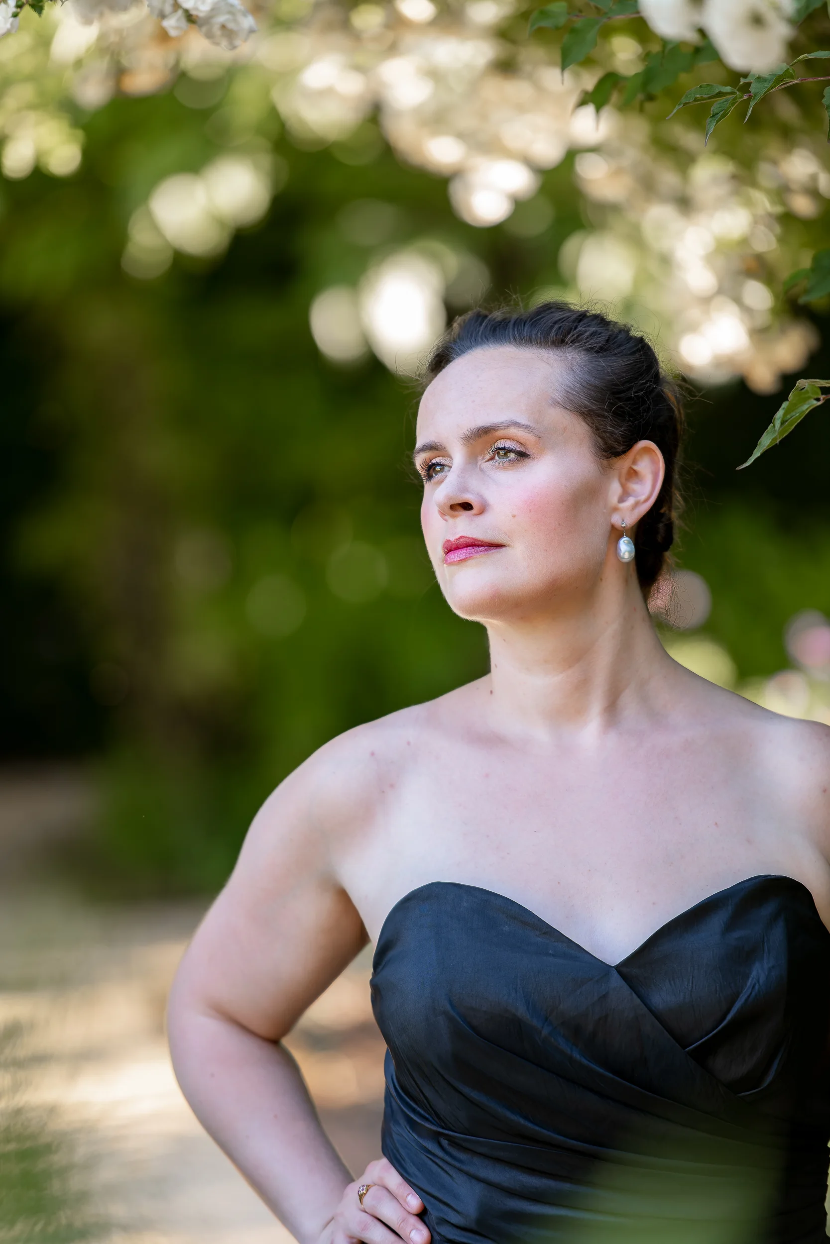 Katy Thomson in a black evening dress beneath flowering branches