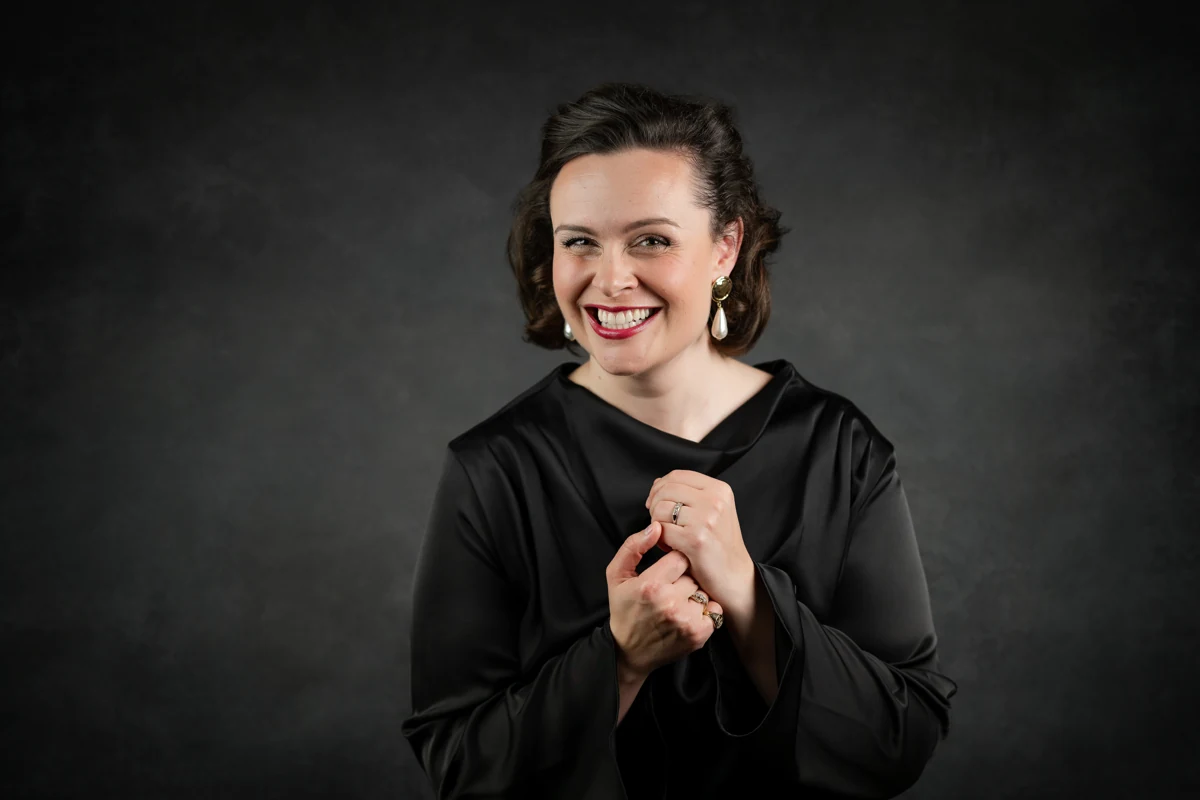Katy Thomson smiling in a black draped outfit