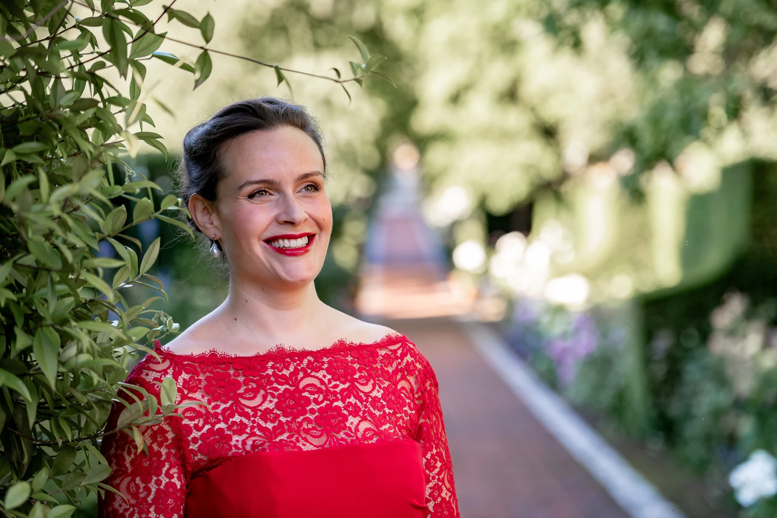Katy Thomson wearing a red lace dress in a garden