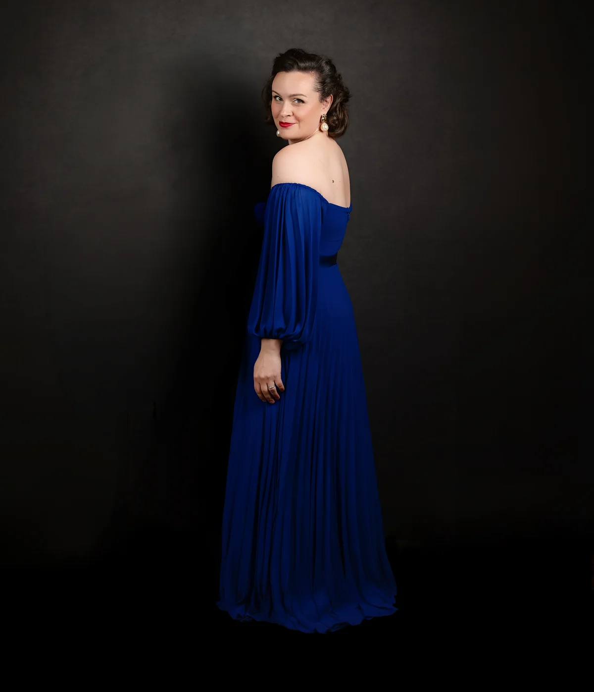 Katy Thomson standing in a full-length cobalt blue gown
